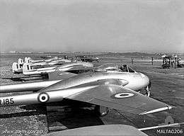 Row of single-engined fighter aircraft with twin tail booms, parked on airfield