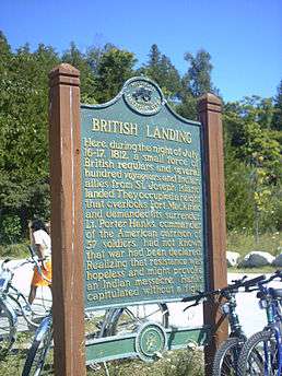 A historical plaque at British Landing, mounted atop wooden poles. Bikes are chained to the poles.