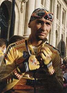 A cyclist wearing a yellow jersey while in the process of unzipping his jersey.