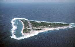 An airstrip and a red and white antenna mast on a small, green, triangular island