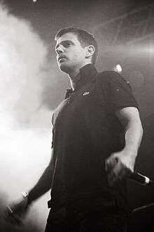 Black-and-white photograph of The Streets lead singer Mike Skinner performing live in 2011.