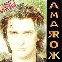 The Amarok album cover. It shows a photograph of Oldfield's face along with a red stamp containing his name at the top left. The left side is the name Amarok in gold coloured capital letters where each letter is made up of a mirror image; the letters A, M nad O appear normally, but R and K have their mirror image also left side of the vertical stick of the letter.