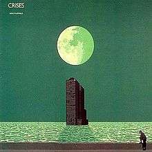 A green coloured seascape with a large moon in the upper centre of the image above a tower building rising out of the sea. The building casts a shadow from the moonlight onto the water. At the bottom of the image a man stands with one foot on a wall.