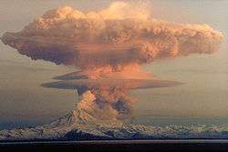 A large ash cloud rising into the air from an erupting volcano