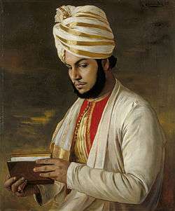 Karim in a turban and holding a book