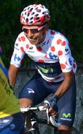 Nairo Quintana wearing a white cycling jersey with red polka dots.