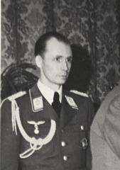 A black-and-white photograph of a man wearing a military uniform and adjutant ribbons on his right shoulder.