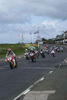 Several motorcycle riders racing on a public road