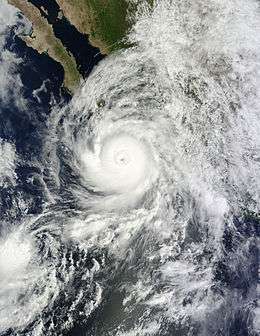 A well developed hurricane approaching Baja California, Mexico, from the south. It features a mostly circular cloud mass surrounding a defined eye.