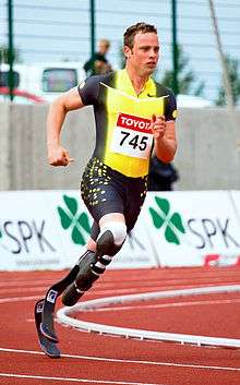 Photograph of Oscar Pistorius sprinting around a track with two carbon fibre transtibial artificial limbs.