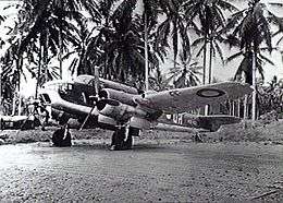 Three-quarter view of twin-engined military aircraft on jungle landing