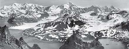  Aerial view of icy mountain-tops and valleys, water in foreground