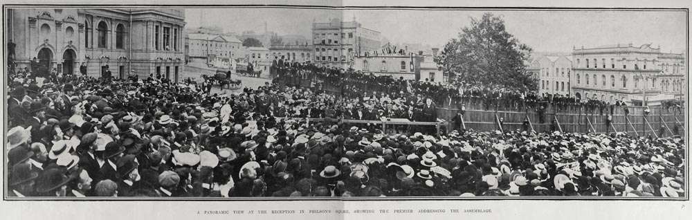 Panoramic view of a large crowd assembled in front of group of speakers