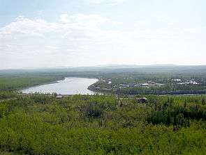 A wide river winds through a forest and by a town.