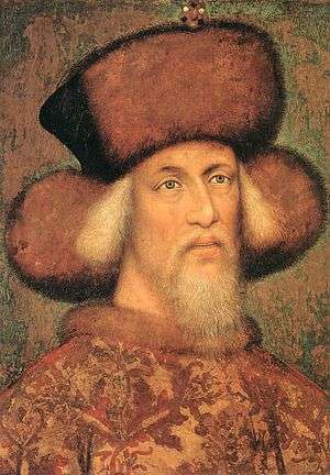 An elderly bearded man wearing a hat made of fur