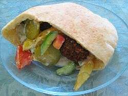 A pita filled with vegetables and fritters on a plate