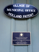 Plaques on Holland Patent Train Station. The first one reads "Village of Holland Patent Municipal Office." The second one reads "NYS Environmental Protection Fund Holland Patent Railroad Depot Restoration, 2003. George E. Pataki, Governor; Bernadette Castro, Commissioner; Michael J. Bennison, Mayor."