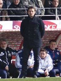 A photograph of Rémi Garde, standing in the managerial dugout.
