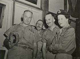 Informal half-portrait of three men and a woman in light-coloured uniforms