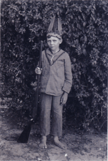 Black and white photograph of a boy dressed in a native American costume.