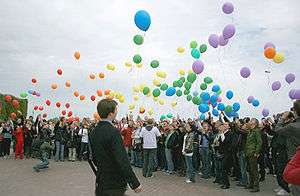 Large group of people releasing multicolored balloons