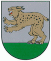 A coat of arms depicting a golden lynx with black spots, a red tongue, white teeth, and white claws standing on its back paws on green turf