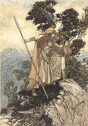 A youthful valkyrie, wearing armour, cloak and winged helmet and holding a spear, stands with one foot on a rock and looks intently towards the right foreground. In the background are trees and mountains.