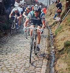 A cyclist riding on a cobbled road
