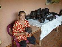 Doña Rosa Brítez with her blackware pottery seated on plastic chair