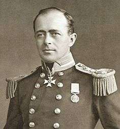  Man with receding hairline, looking left, wearing naval uniform with medals, polished buttons and heavy shoulder decorations