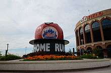 A sculpture of a red apple with the New York Mets logo on it rises above a black pedestal with the words "Home Run" in large letters.