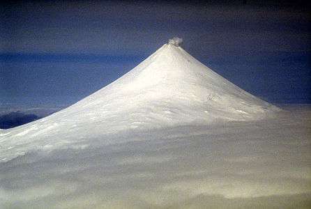 A snow-covered mountain with a small puff of steam rising from the top