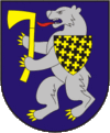 A coat of arms depicting an angry, grey bear with yellow claws and a long, red tongue gripping a yellow axe in its paws all on a blue background