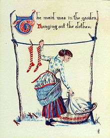 woman in patterned dress with lifted petticoats hangs using left hand to hang a sock from a laundry line while bending down to lift a garment from a laundry basket with right hand