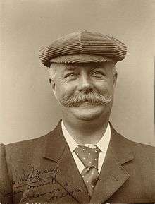 Head and shoulders portrait of a man in his fifties with moustache wearing a hat