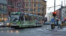 A tram with advertisements at a busy intersection