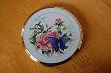 Circular brass container with lid depicting a rose and a butterfly