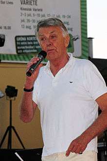 Photograph of Sven-Bertil Taube on a stage, holding a microphone