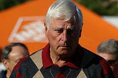 A gray-haired man wearing a red-, black- and tan-checkered sweatshirt