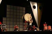 Members of Brazilian group Seiryu Daiko performing on stage with a variety of taiko.
