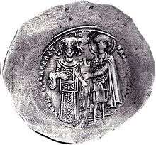 Round silver coin with two standing figures, the left one dressed in regalia and the right one as a warrior saint, handing a castle to the former