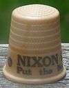 An off-white thimble, with the visible black lettering, "NIXON/Put the ne ...