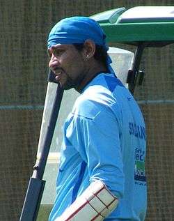 A man in his 30s, wearing a blue cloth on his head, and a blue top.