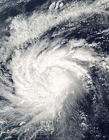 Satellite image of a sprawling tropical cyclone, centered at the image's center. The white clouds of the storm takes up most of the image, with dark blue season visible on the image's extremities.