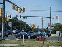 A  congested signalized intersection between two roads. A sign on the traffic light pole reads south left Route 47 north right while a shield in the distance reads south U.S. Route 9.