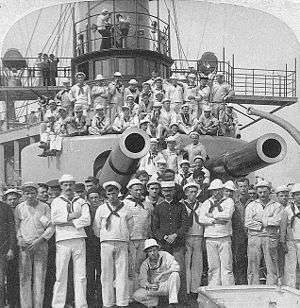 crewmen pose under gun turrets of the USS Iowa