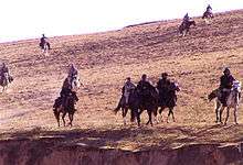 Ten horses with riders on the side of a hill