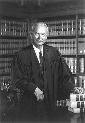 Photograph of an older white male standing, in judicial robes