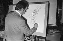 A man drawing a cartoon character on a large vertical drawing board