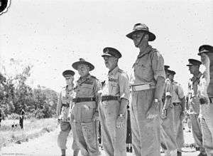 A group of soldiers in shirt sleeves stand at attention.